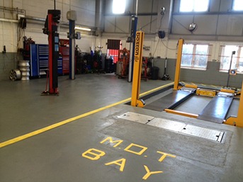 Inside the MVS workshop: two-post lifts and the yellow-painted MOT bay with its test ramp